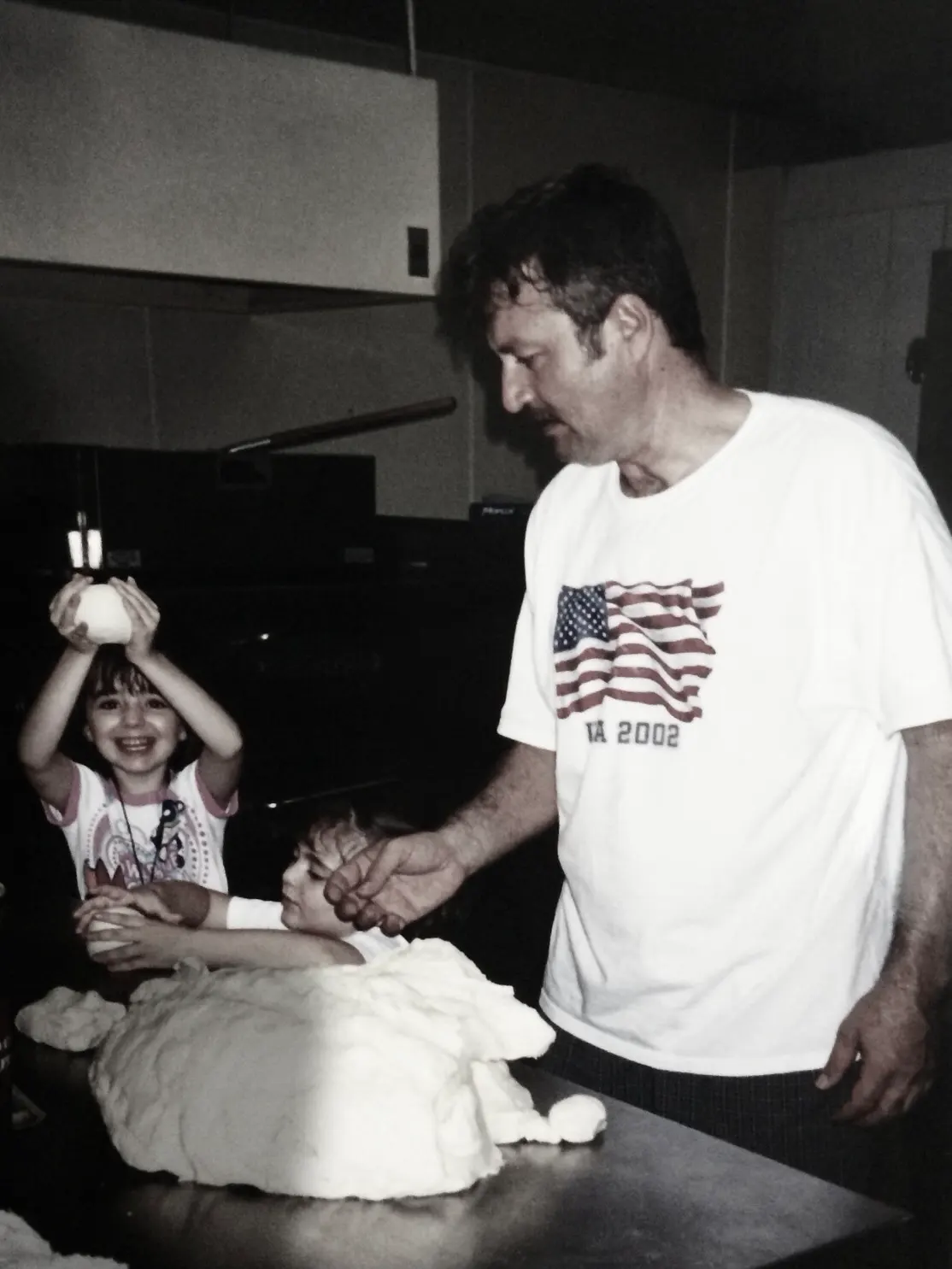 A guy and two kids preparing pizza dough.